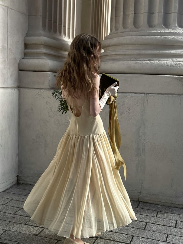 A woman in a yellow dress is walking down the street