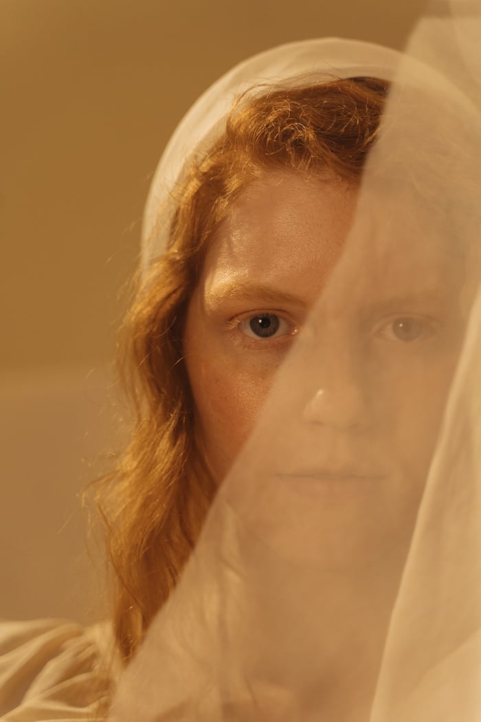 A Woman Behind Lace Fabric while Seriously Looking at the Camera